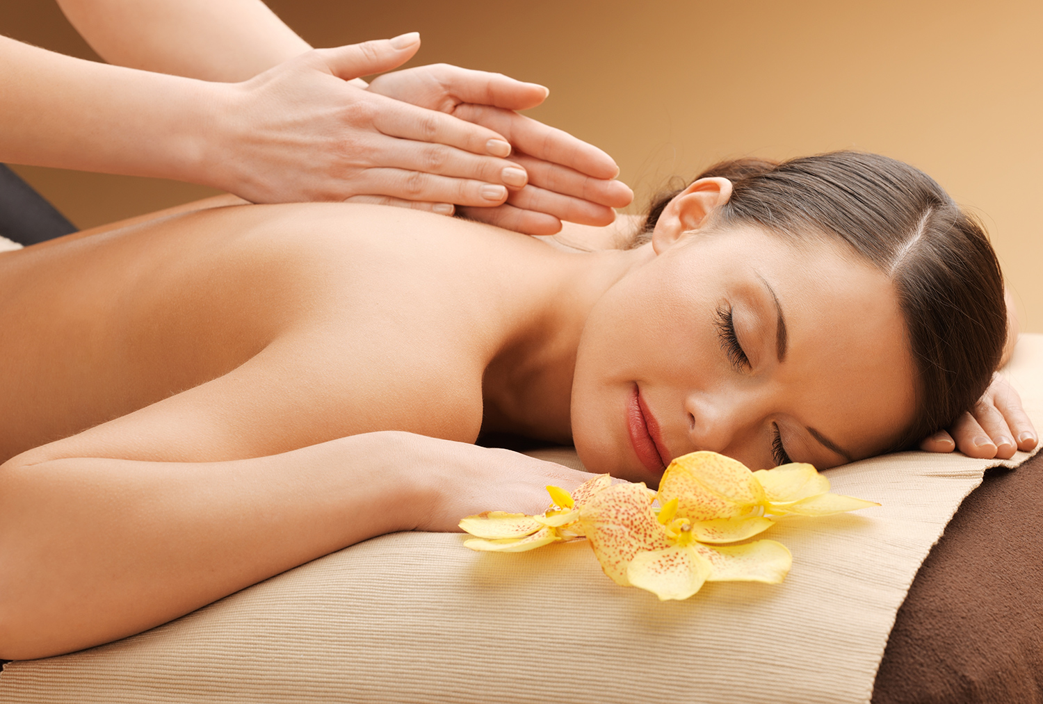Massage treatment with yellow orchids nearby